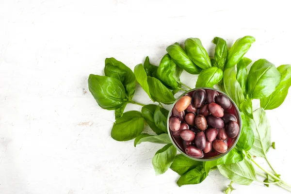 Aceitunas Kalamata en el plato de cerámica y la albahaca verde —  Fotos de Stock