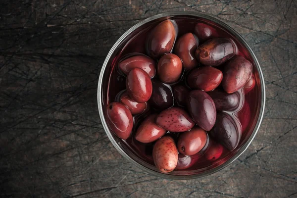 Kalamata olives on the glass dish on the old wooden table — Stock Photo, Image