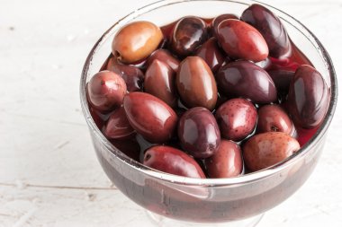 Kalamata olives on the glass bowl on the old wooden table clipart