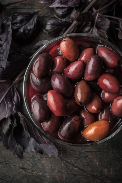 Aceitunas Kalamata en el plato de vidrio con albahaca roja vertical — Foto de Stock