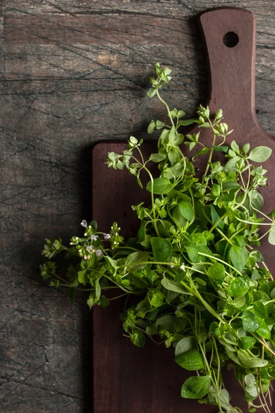 Oregano w zarządzie kuchnia na stary stół ciemny pionowy — Zdjęcie stockowe