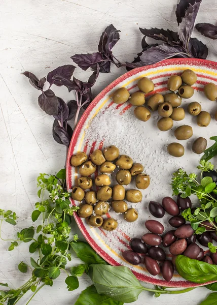 Assorted olives on the ceramic plate with different greens — Stock Photo, Image