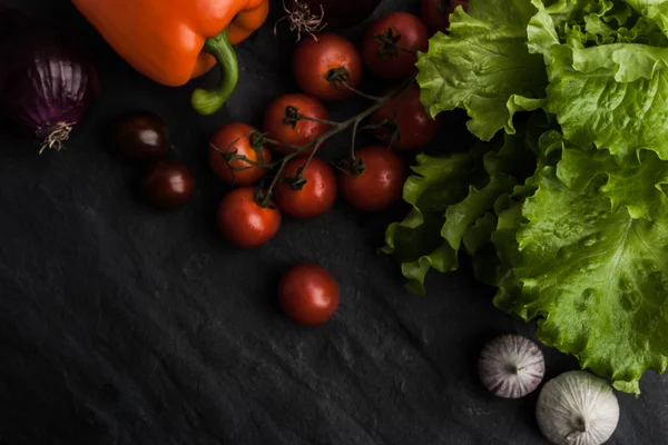 Gemüsemischung mit grünem Salat auf dem schwarzen Steintisch — Stockfoto