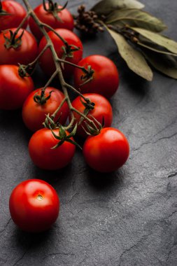 Siyah taş masanın üzerine defne yaprağı ile domates dal