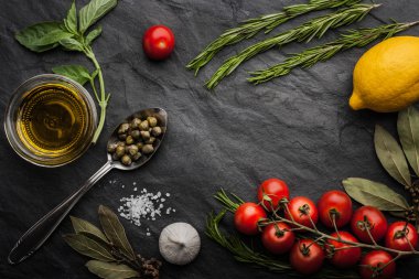 Herbs mix with tomatoes, lemon and olive oil on the black stone table clipart