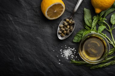 Olive oil with lemon , capers and different greens horizontal