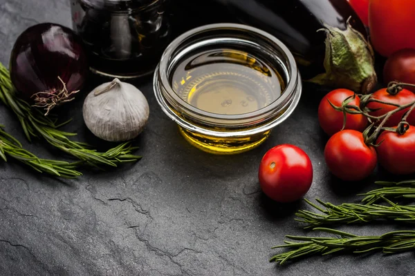 Mezcla vegetal con aceite de oliva y romero en la mesa de piedra negra —  Fotos de Stock