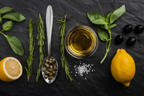 Herbs mix with  lemons , capers and olives on the black stone table Stock Image