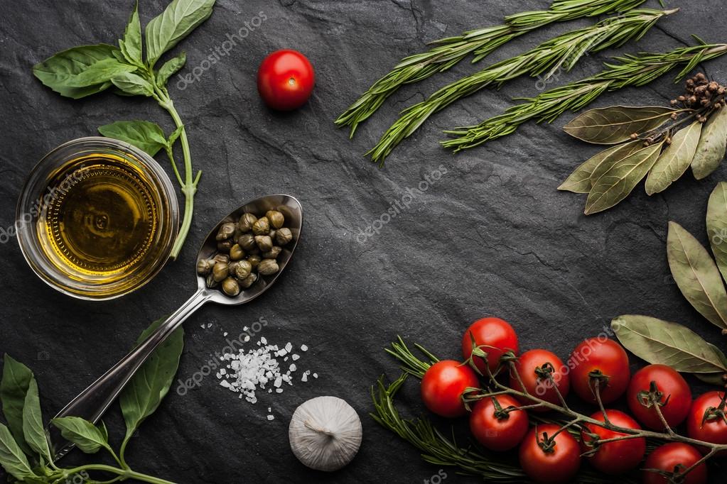 Herbs mix with tomatoes and olive oil on the black stone table Stock