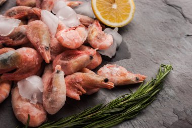 Frozen shrimps  with lemon and rosemary on the black stone table horizontal
