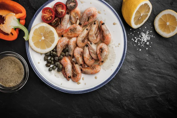 Grilled prawns with tomatoes , sweet pepper and capers on the ceramic plate — Stock Photo, Image