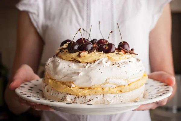 Pavlova tårta med färska körsbär i kvinna händerna horisontella — Stockfoto