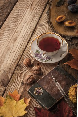 Plums, nuts and leaves with vintage notebook and tea with film filter effect vertical