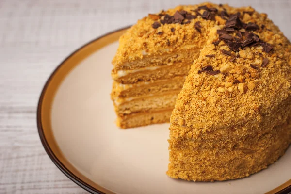 Honey cake with chocolate chips and a slice cut out — Stock Photo, Image