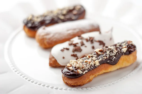 Chocolate e baunilha eclairs na placa de cerâmica — Fotografia de Stock