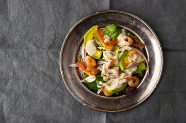 Karides ve gri masa örtüsü üzerinde vintage metal plaka üzerinde Avokado salatası