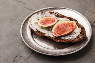 Bread with fresh cheese , fig and thyme on the vintage metal plate
