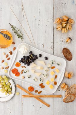 Cheese platter with different fruits , nuts and honey top view