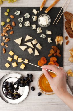 Cheese and fruit mix on the black stone with woman hand
