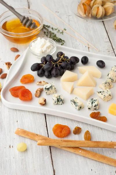 Sortidas com queijo, frutas e nozes na mesa de madeira branca — Fotografia de Stock