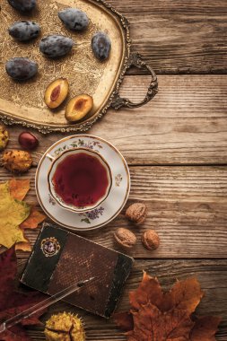 Plums , nuts and leaves with vintage notebook and tea with film filter effect top view