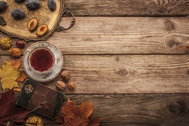 Plums , nuts and leaves with vintage notebook and tea with film filter effect background