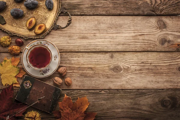 Susine, noci e foglie con taccuino vintage e tè con pellicola effetto filtro sfondo — Foto Stock