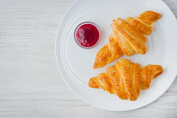 Dois croissants com geléia de baga na vista superior da placa cerâmica branca — Fotografia de Stock