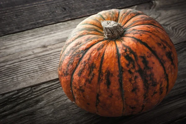 Zucca arancione con strisce verdi sul tavolo di legno orizzontale — Foto Stock