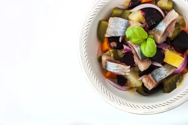 Vegetable salad with herring on the white ceramic dish top view — Zdjęcie stockowe