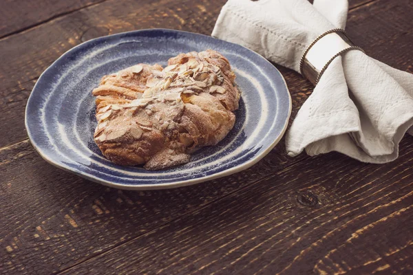 Croiisant with almond on the ceramic plate with napkin — Stok fotoğraf