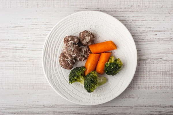 Brócoli al vapor y zanahorias con albóndigas en el plato blanco vista superior —  Fotos de Stock