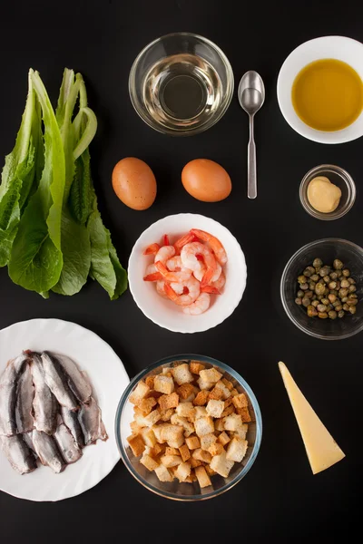 Ingredients for Caesar salad on the black background vertical — Stock Photo, Image