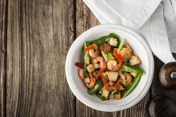 Caesar salad with prawns on the wooden table top view — Stock Photo, Image