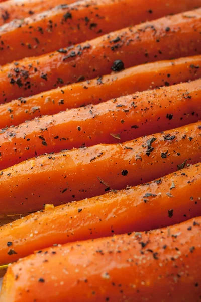Baked carrots woth blsck pepper and herbs close-up bacground vertical — Stock Photo, Image