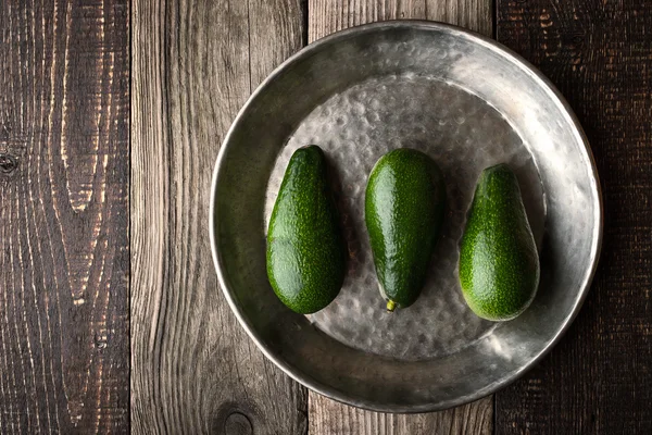 Aguacate en la placa de metal en la mesa de madera vista superior horizontal — Foto de Stock