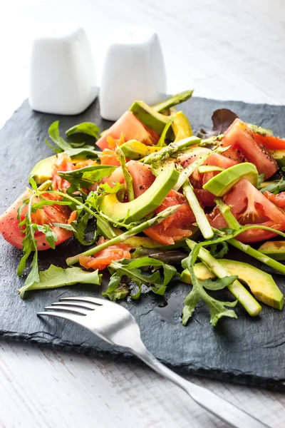 Ensalada de verduras con trucha y espárragos en la piedra negra con tenedor vertical —  Fotos de Stock