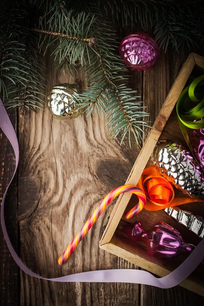 Wooden box with Christmas tree decorations and candy vertical — Stock Photo, Image