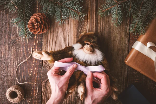 Tying violet ribbon on a monkey toy horizontal — Stock Photo, Image