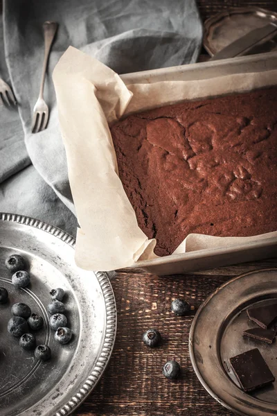 Pastel de chocolate en la bandeja para hornear con arándanos y vajilla —  Fotos de Stock