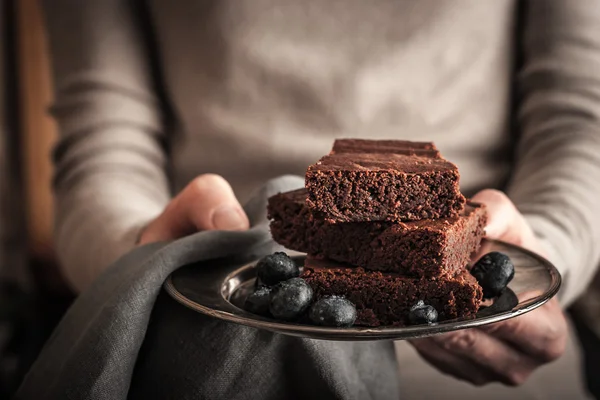 Chocolate brownie with blueberry in the hands — Stock Photo, Image