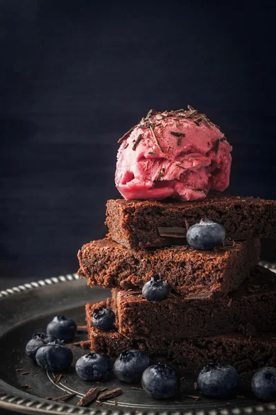 Шоколадное пирожное с черникой и мороженым на винтажной пластине вертикально — стоковое фото