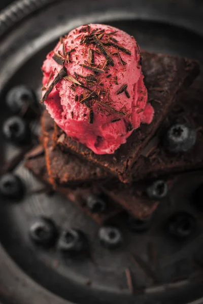 Brownie de chocolate desenfocado con arándanos y helado en la placa vintage vertical — Foto de Stock