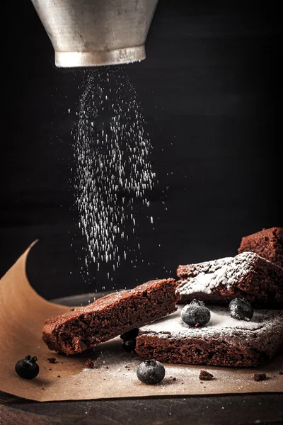 Sprinkling chocolate brownie com açúcar de confeiteiro e mirtilo — Fotografia de Stock