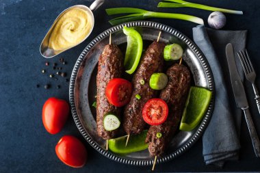 Vintage metal plaka üstüne sebzeli kebap görüntülemek