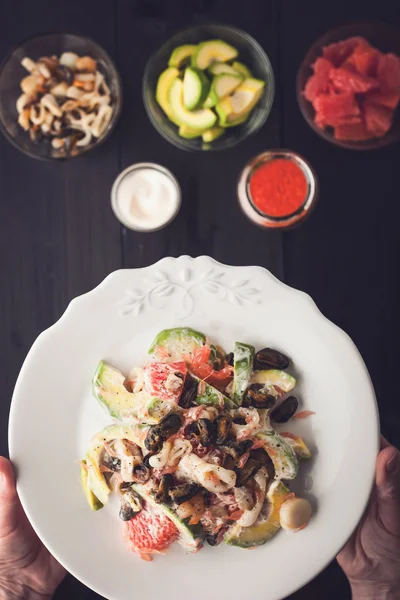 Seafood salad in the hand with blurred ingredients top view — Stock Photo, Image