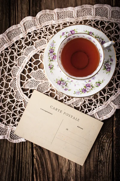 Xícara de chá com cartão postal na mesa de madeira — Fotografia de Stock