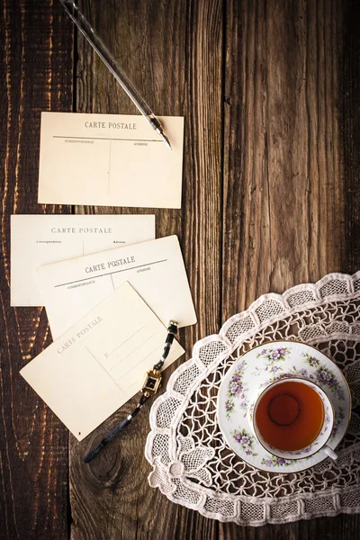 Postais com xícara de chá na mesa de madeira vertical — Fotografia de Stock