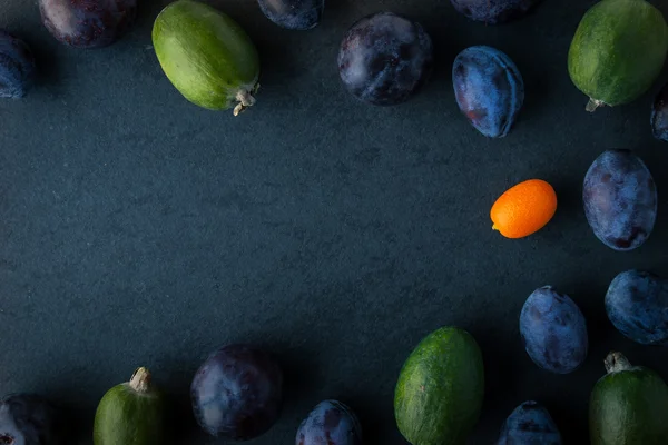 Pflaumen und Feijoa auf dem dunklen Tisch — Stockfoto