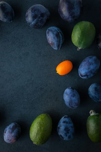 Śliwki i feijoa na stole ciemny pionowy — Zdjęcie stockowe